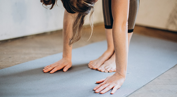 Femme qui fait des étirements sur un tapis de sport.