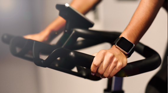 Femme avec une montre connecté sur un vélo d'appartement.