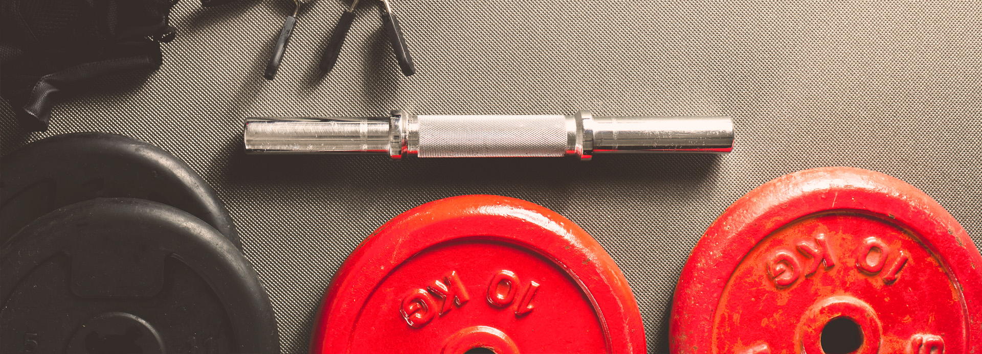 Lot de deux poids rouges de 10 kilos et leur barre d'haltère.