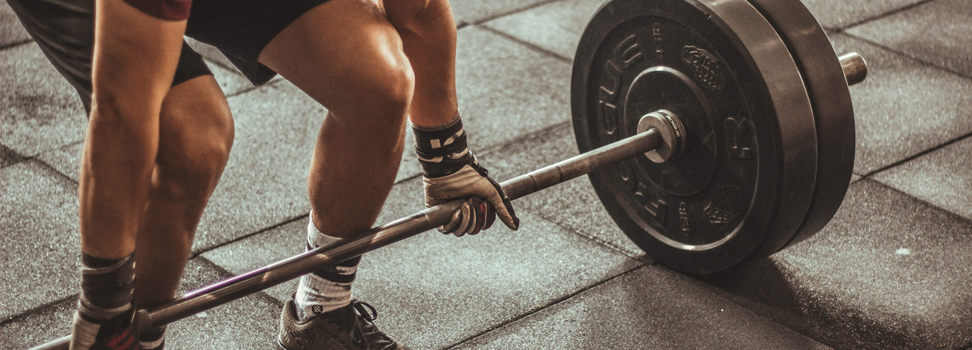 Homme soulevant une barre de musculation noire.