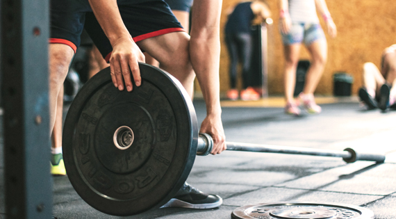 Homme en train de monté une barre de musculation.